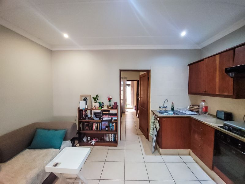 Open-plan living area featuring a functional kitchen with built-in cabinetry, oven, and extractor fan, finished with tiled flooring throughout.