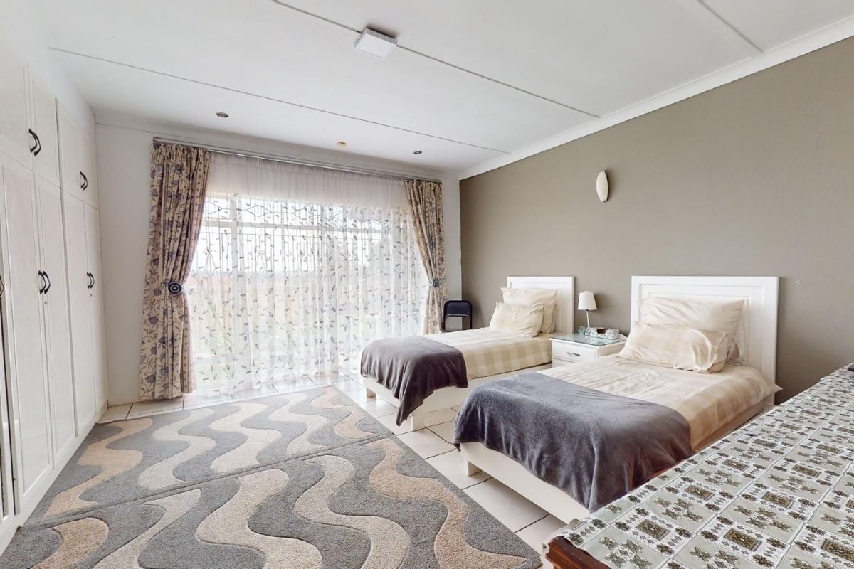 Spacious bedroom featuring built-in cupboards, tiled flooring, and a large sliding glass door providing natural light.