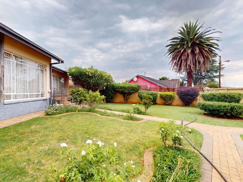 A well-maintained rear garden featuring a paved walkway, established lawn, and brick boundary wall, providing a private outdoor space.