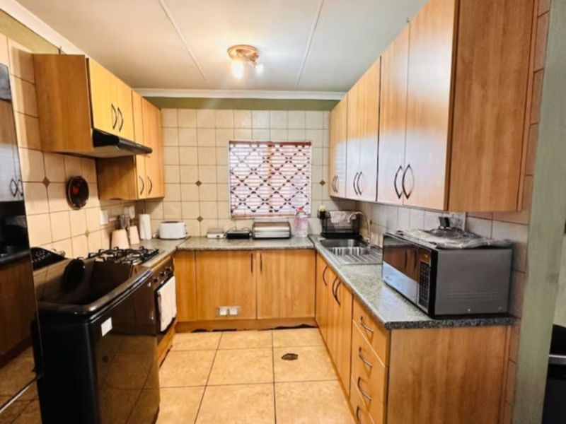 A functional kitchen featuring laminate cabinetry, granite countertops, tiled backsplash, and built-in cooking appliances, offering a practical layout for daily meal preparation.