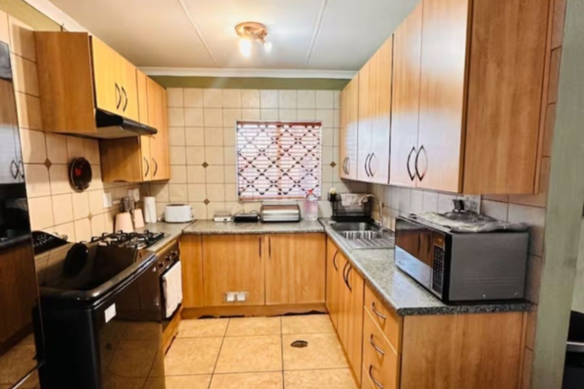 A functional kitchen featuring laminate cabinetry, granite countertops, tiled backsplash, and built-in cooking appliances, offering a practical layout for daily meal preparation.