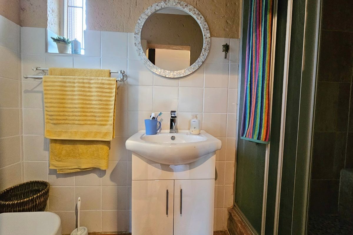 A functional bathroom featuring a vanity cabinet with a basin, a shower enclosure, and tiled wall finishes.