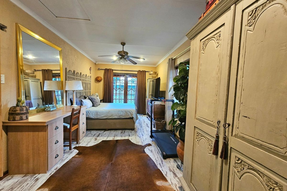 Spacious bedroom featuring a ceiling fan and direct access to the outdoors through a sliding glass door with security gate.