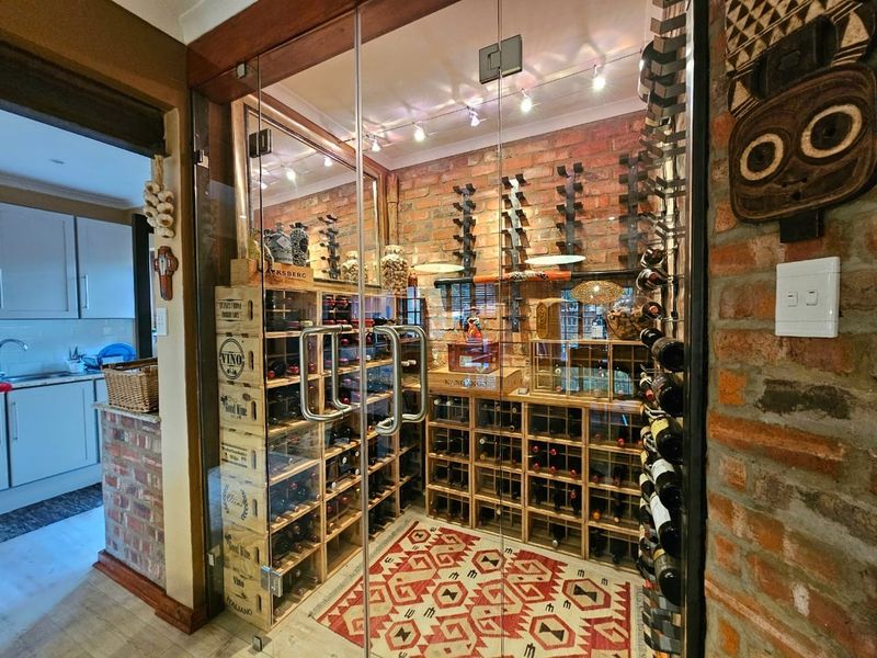 A custom-built glass-enclosed wine cellar featuring exposed brick walls and integrated timber wine racking with professional lighting.