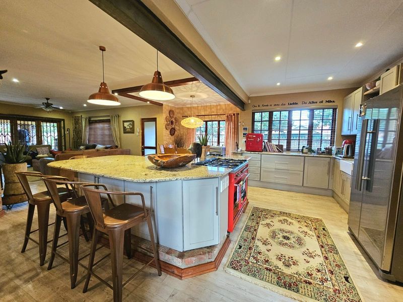 Spacious open-plan kitchen and living area featuring a large granite island, gas cooktop, and modern cabinetry with integrated lighting and exposed structural elements.