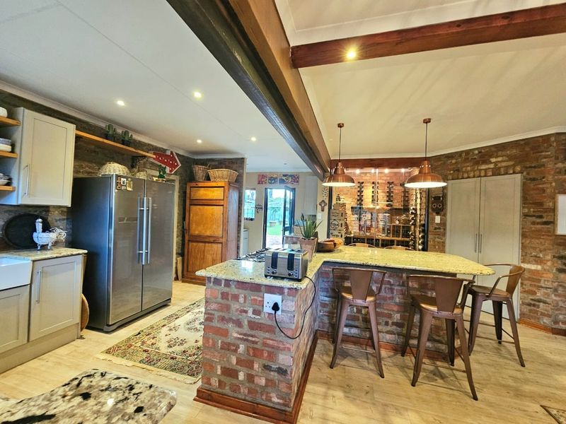 Spacious kitchen featuring exposed brick walls, granite countertops, a central island with breakfast bar seating, and warm pendant lighting.