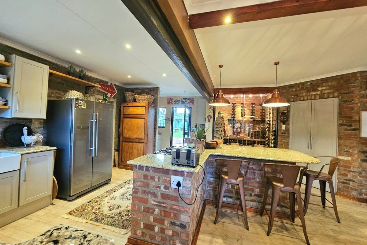 Spacious kitchen featuring exposed brick walls, granite countertops, a central island with breakfast bar seating, and warm pendant lighting.
