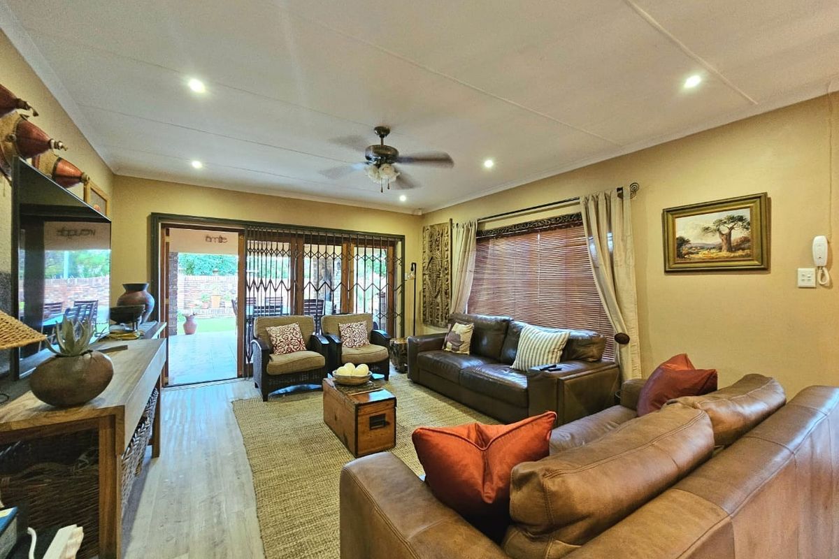 A comfortable living room featuring laminate flooring, recessed lighting, a ceiling fan, and sliding glass doors that open to an outdoor patio area.