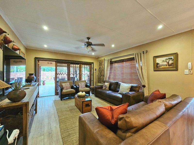 A comfortable living room featuring laminate flooring, recessed lighting, a ceiling fan, and sliding glass doors that open to an outdoor patio area.