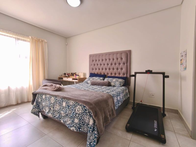 A well-lit bedroom featuring neutral tiled flooring and a clean, minimalist aesthetic, providing a comfortable and functional living space.