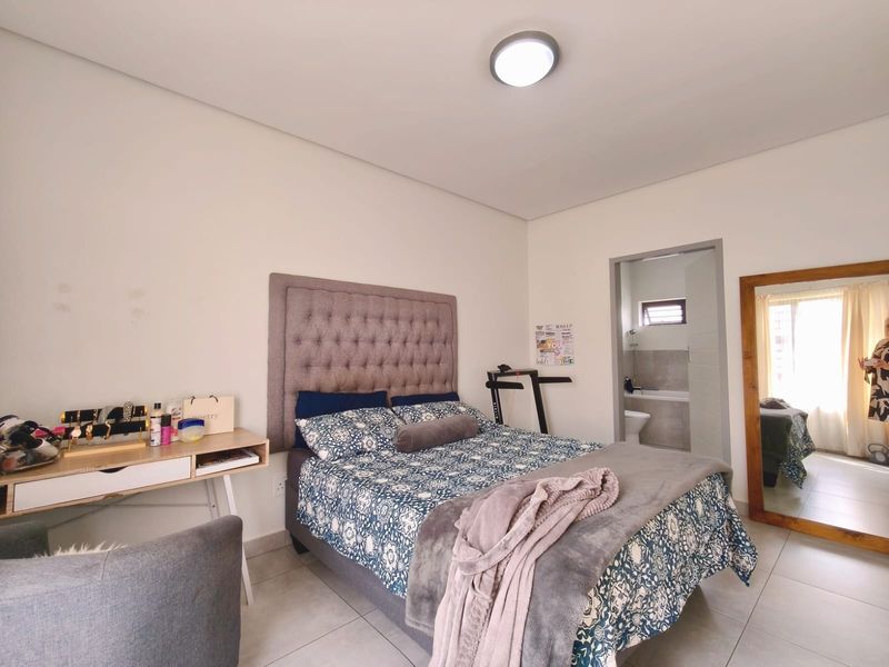 A well-maintained bedroom featuring tiled flooring, a neutral color palette, and direct access to an en-suite bathroom.