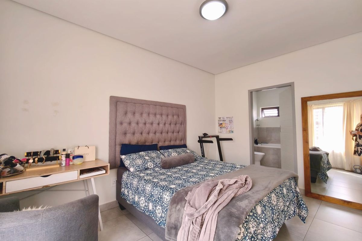 A well-maintained bedroom featuring tiled flooring, a neutral color palette, and direct access to an en-suite bathroom.