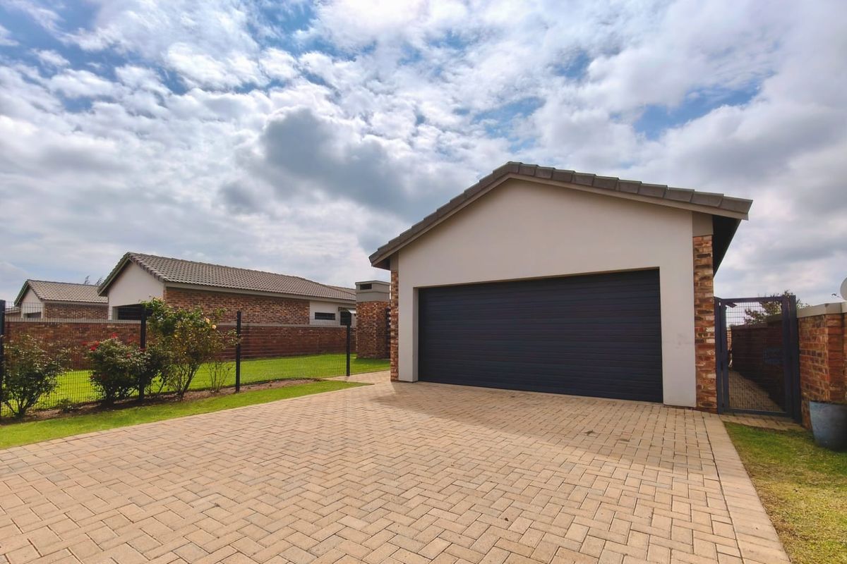 A well-maintained detached garage featuring a paved driveway, brick exterior, and a modern sectional garage door.