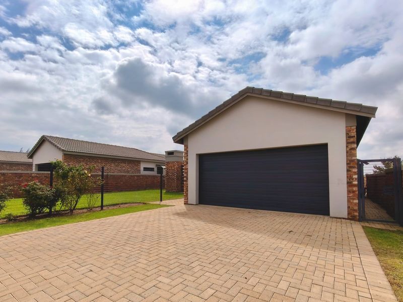A well-maintained detached garage featuring a paved driveway, brick exterior, and a modern sectional garage door.