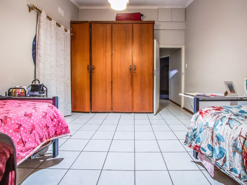 A bedroom featuring tiled flooring and a large built-in wooden wardrobe, providing ample storage space.