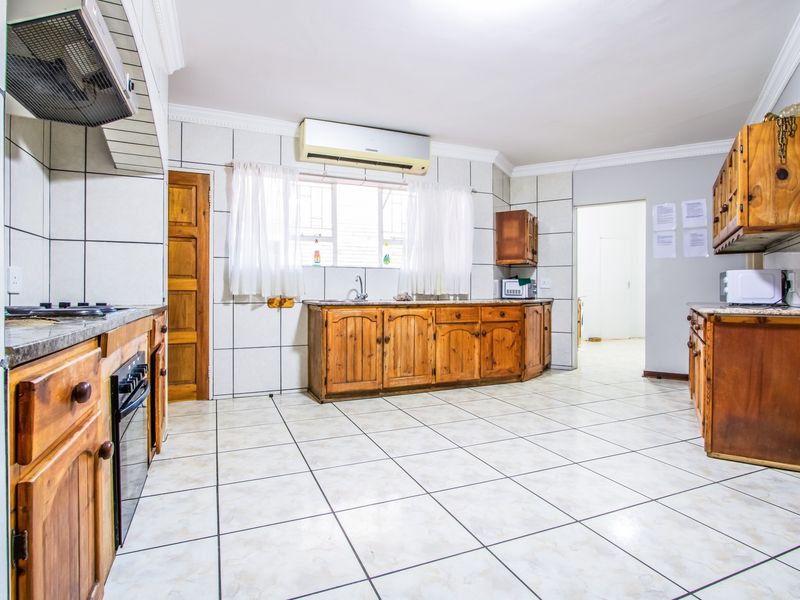 Spacious kitchen featuring wooden cabinetry, granite countertops, built-in oven, gas hob, and tiled finishes throughout.
