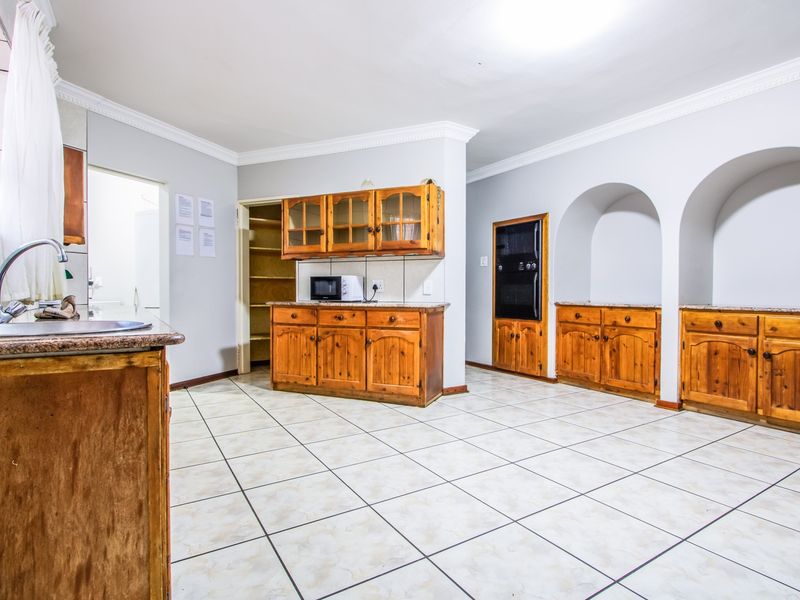 Spacious kitchen featuring extensive wooden cabinetry, granite countertops, built-in oven, and a convenient walk-in pantry with tiled flooring throughout.