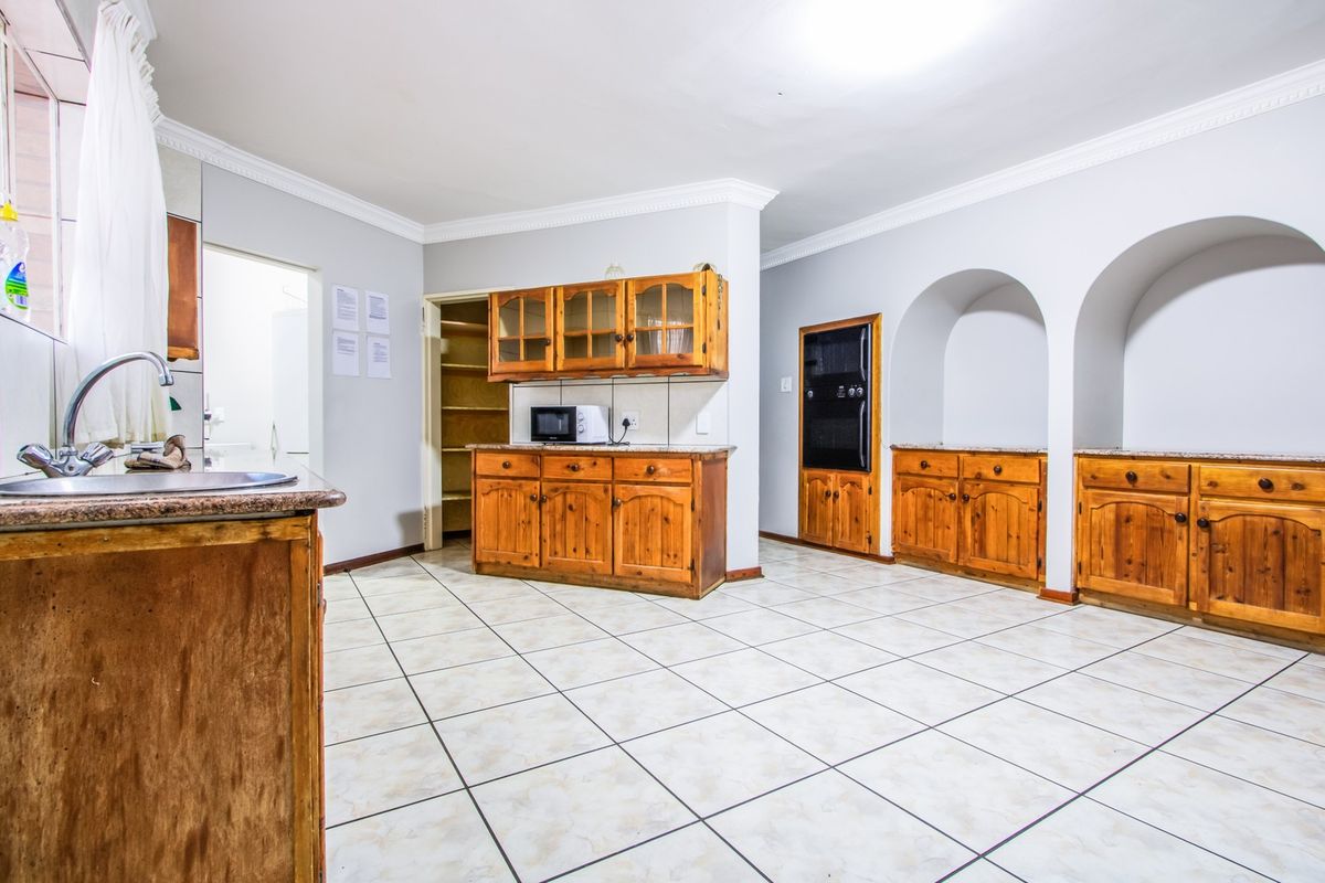 Spacious kitchen featuring extensive wooden cabinetry, granite countertops, built-in oven, and a convenient walk-in pantry with tiled flooring throughout.