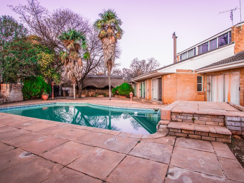Rear exterior view featuring a swimming pool, paved patio area, and brick house facade with sliding door access.