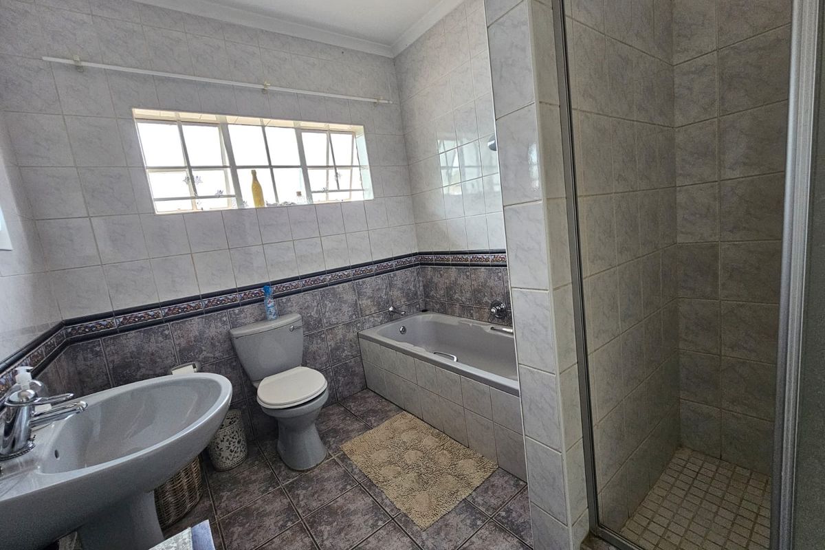 A functional bathroom featuring a pedestal basin, toilet, bathtub, and a separate shower enclosure with tiled finishes throughout.
