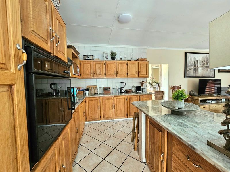 A functional kitchen featuring traditional wooden cabinetry, stone-look countertops, a central island, and an integrated eye-level oven, offering a classic layout with potential for modernization.
