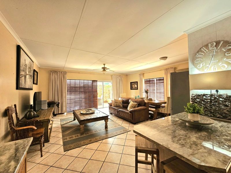 Spacious open-plan living and kitchen area featuring tiled flooring, a central kitchen island with stone countertops, and direct access to the outdoor patio.