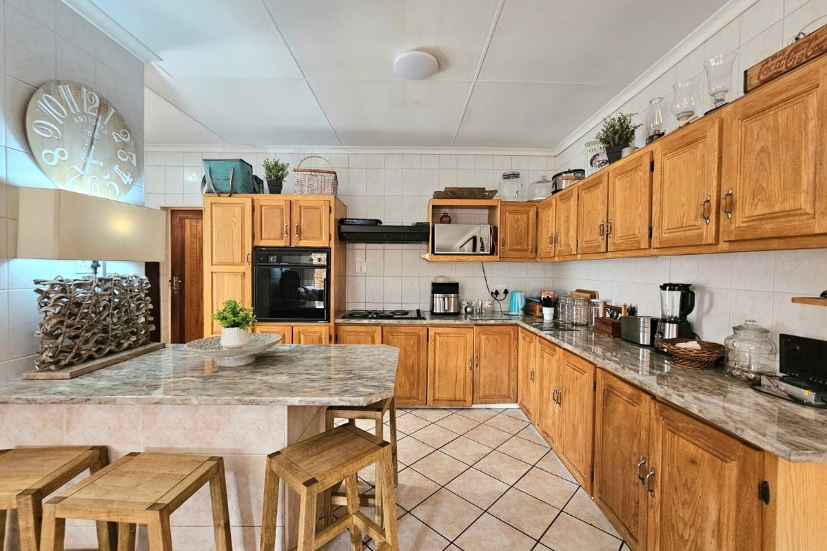 A functional kitchen featuring traditional wooden cabinetry, stone countertops, a built-in oven, gas hob, and a convenient breakfast nook with tiled flooring.
