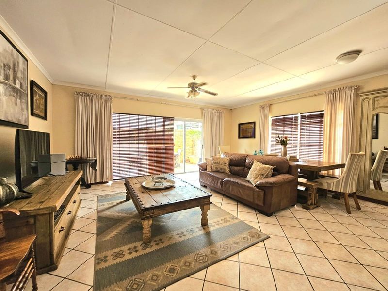 Spacious open-plan living and dining area featuring tiled flooring, a ceiling fan, and large sliding glass doors providing access to the outdoor space.
