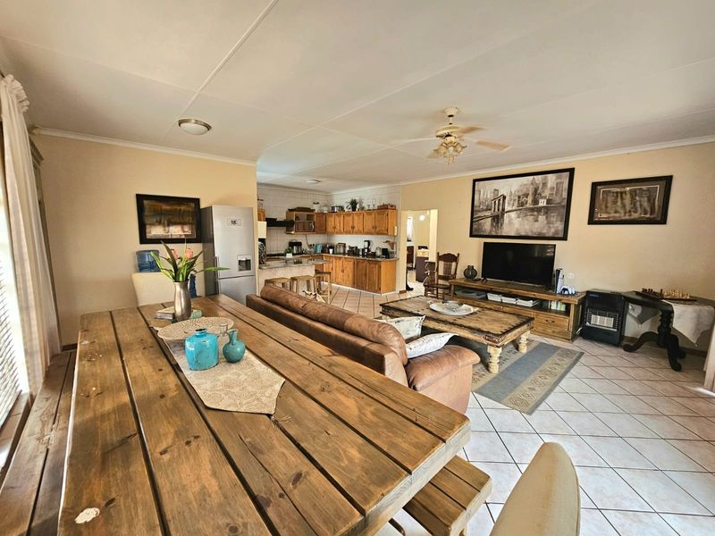 Spacious open-plan living and dining area featuring tiled flooring, a ceiling fan, and a functional kitchen with wooden cabinetry.