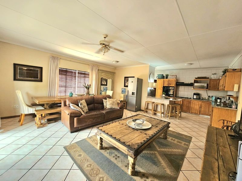 Spacious open-plan living and dining area featuring a functional kitchen with built-in cabinetry, a central island, and tiled flooring throughout.