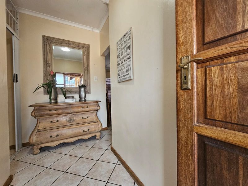 A welcoming entrance hall featuring tiled flooring and a solid wood front door, providing a warm and functional transition into the home.