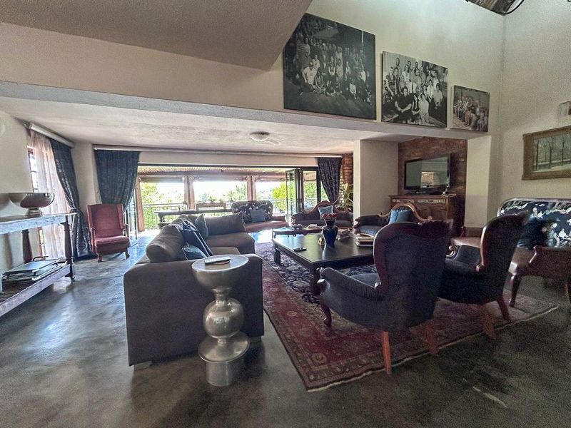 Spacious living room featuring polished concrete floors, a vaulted ceiling, and an exposed brick wall, with large bi-fold doors opening to an outdoor area.