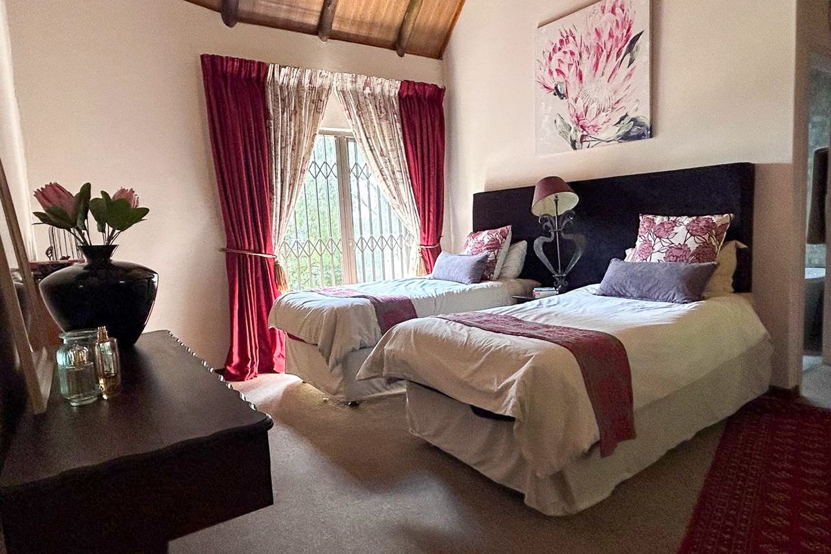 A bedroom featuring a high vaulted timber ceiling, carpeted flooring, and a window fitted with a security gate.