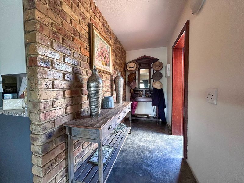 A hallway featuring an exposed brick feature wall and concrete flooring, leading towards an interior doorway.