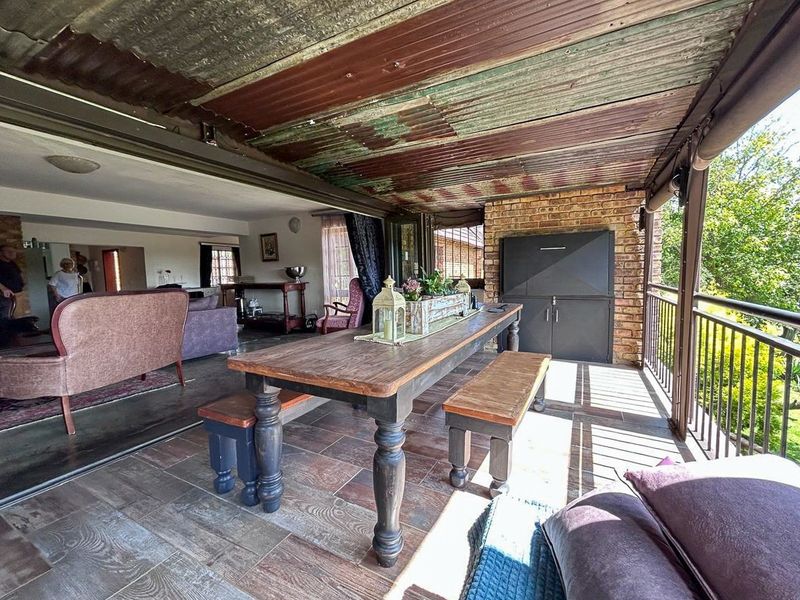 Covered patio area featuring a built-in braai, exposed brick accents, and tiled flooring, providing a seamless transition to the indoor living space.