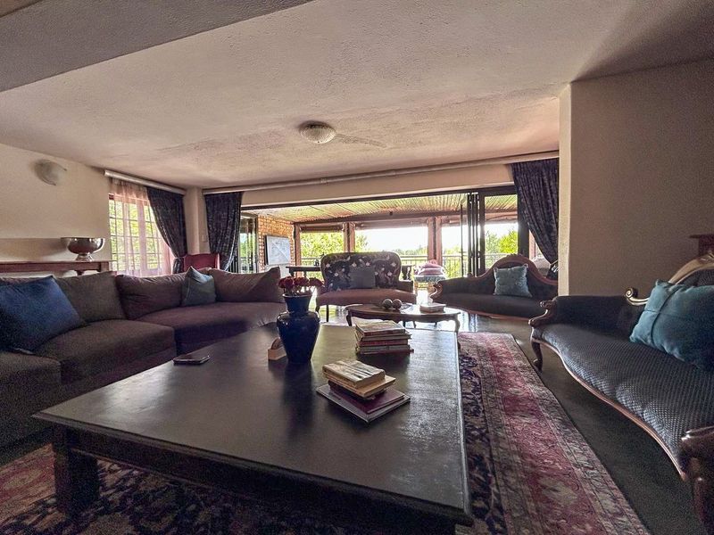 Spacious living room featuring large folding glass doors that open onto a covered patio, providing seamless indoor-outdoor flow and natural light.