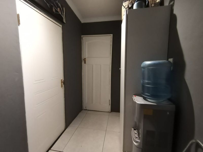 A functional hallway featuring tiled flooring and two white panelled doors, finished with dark grey wall paint.