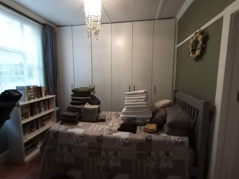 A bedroom featuring built-in floor-to-ceiling cupboards, laminate flooring, and a classic picture rail, offering functional storage space.