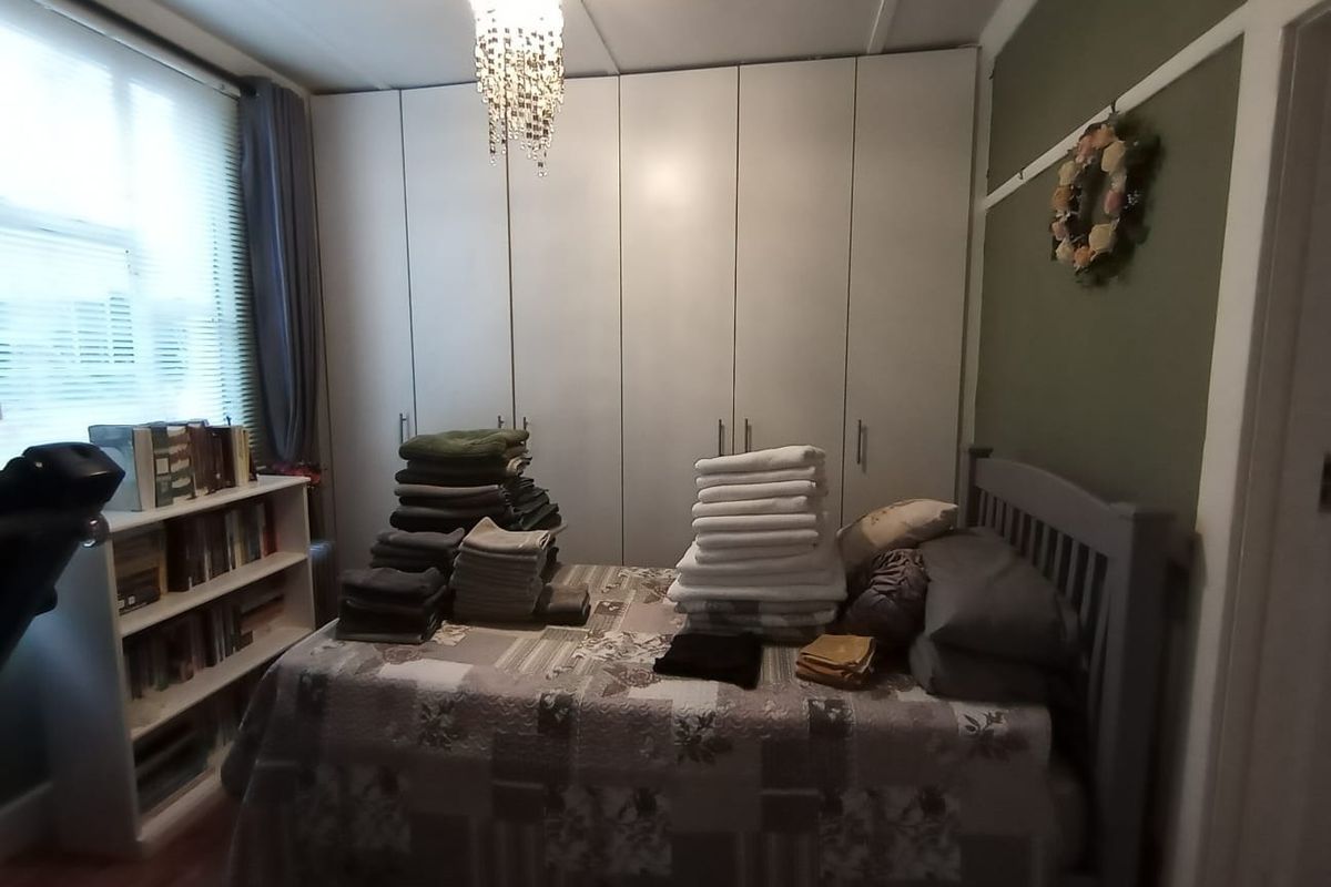 A bedroom featuring built-in floor-to-ceiling cupboards, laminate flooring, and a classic picture rail, offering functional storage space.
