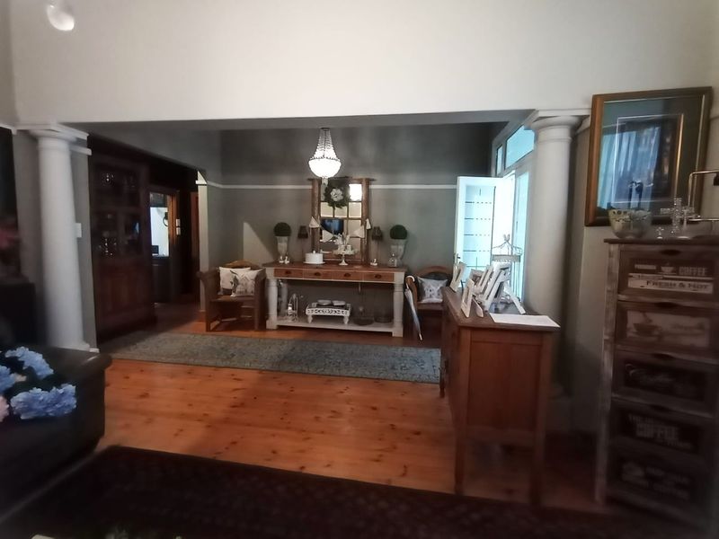 A spacious living area featuring polished hardwood flooring, decorative structural columns, and classic coved ceilings, creating a warm and inviting atmosphere.