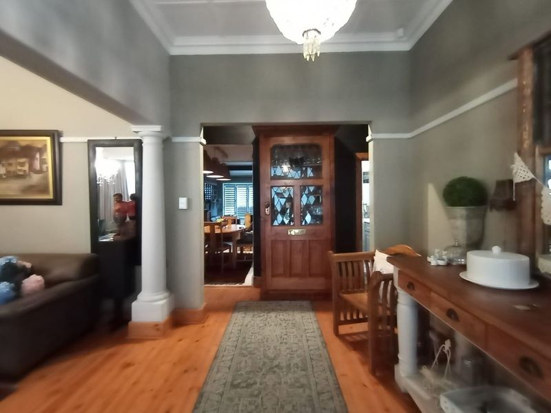 Welcoming entrance hall featuring polished timber flooring, decorative columns, and a classic leaded glass timber front door with period-style crown molding.