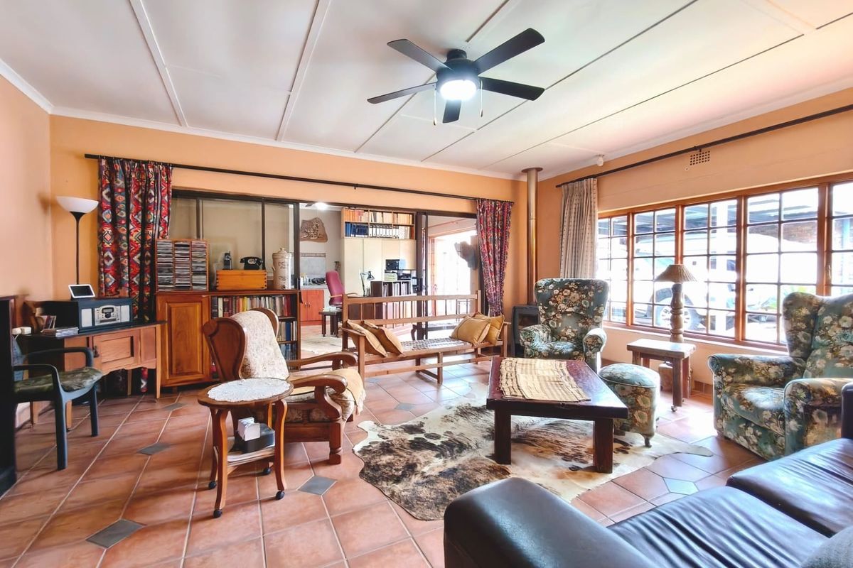 Spacious living room featuring terracotta tiled flooring, a wood-burning stove, ceiling fan, and large windows providing ample natural light.