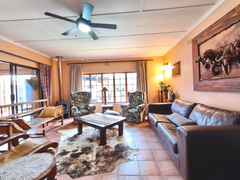 A spacious living room featuring tiled flooring, a wood-burning stove, and large windows that provide ample natural light.