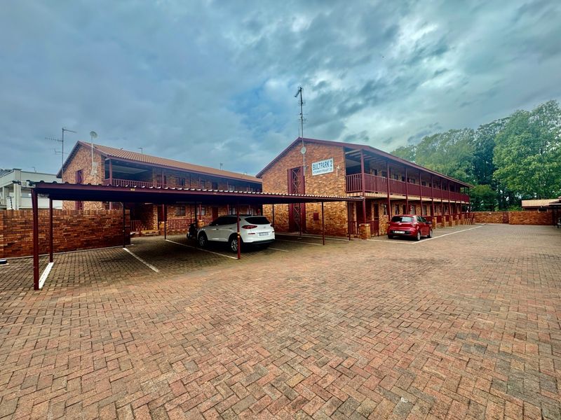 Exterior view of the Bultpark 2 apartment complex featuring brick construction, covered parking carports, and balcony access.