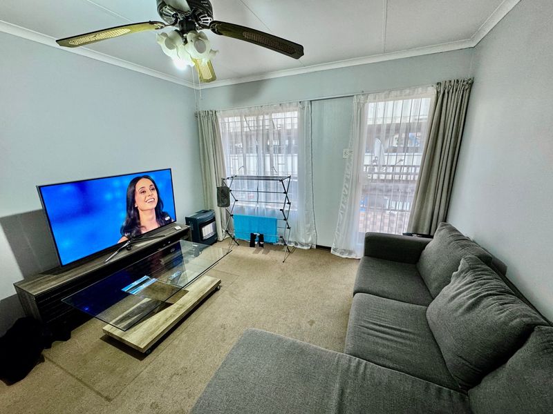 A living room featuring carpet flooring, a ceiling fan, and a sliding glass door providing access to the exterior.
