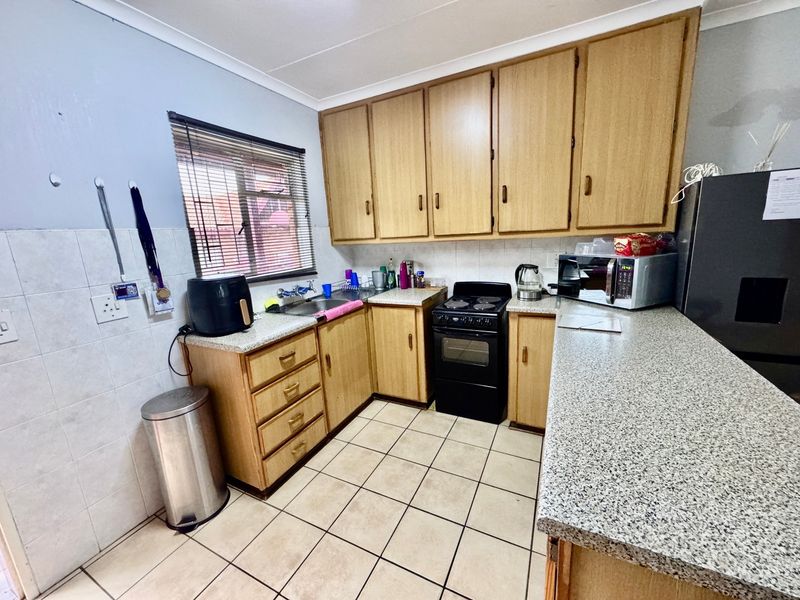 A functional kitchen featuring laminate cabinetry, granite-look countertops, tiled backsplash, and ceramic flooring, offering a practical layout with essential built-in fixtures.