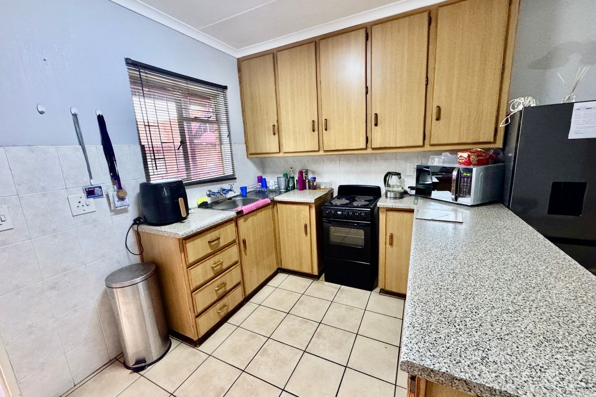 A functional kitchen featuring laminate cabinetry, granite-look countertops, tiled backsplash, and ceramic flooring, offering a practical layout with essential built-in fixtures.