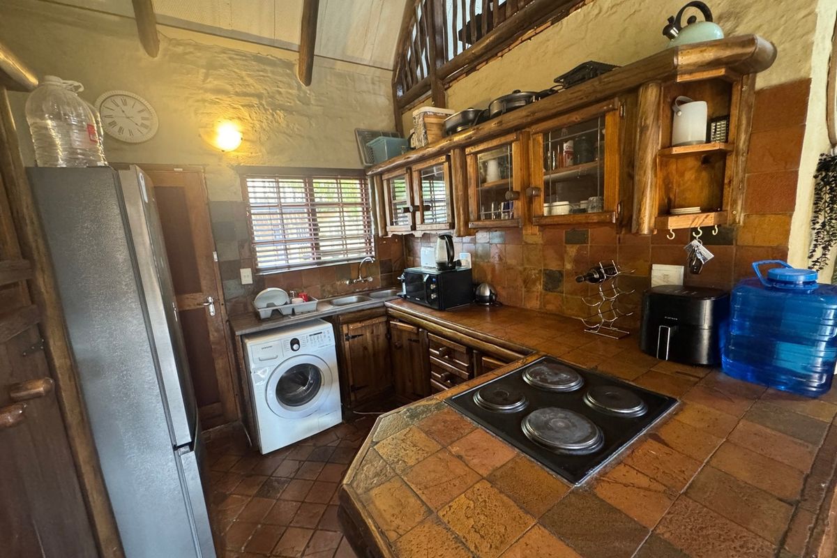 Rustic kitchen featuring wooden cabinetry, tiled countertops, electric hob, and exposed timber ceiling beams in a character-filled apartment setting.