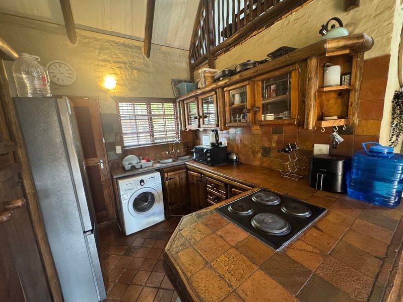 Rustic kitchen featuring wooden cabinetry, tiled countertops, electric hob, and exposed timber ceiling beams in a character-filled apartment setting.