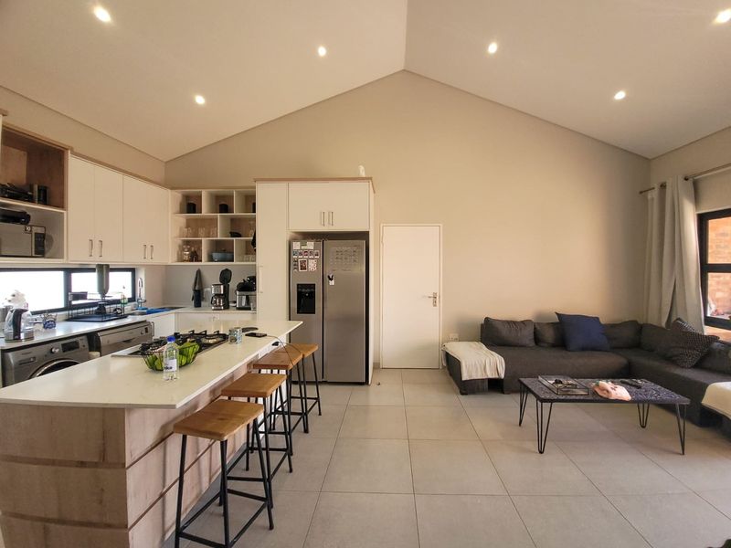Spacious open-plan living area featuring a modern kitchen with stone countertops, gas hob, and a vaulted ceiling, seamlessly flowing into the lounge space.